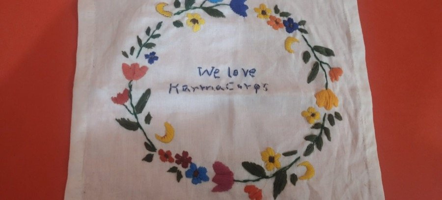 Hand-embroidered cloth reading 'We love KarmaCorps', made by a student