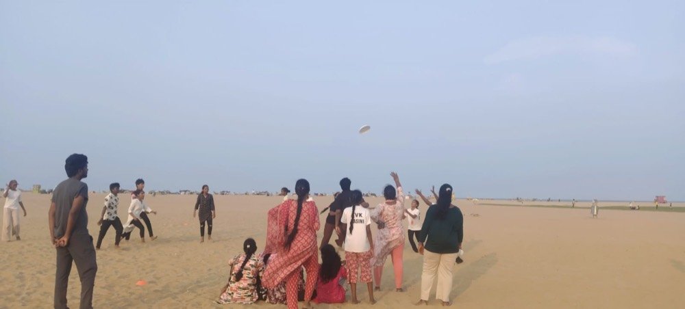 Students playing frisbee together on the beach
